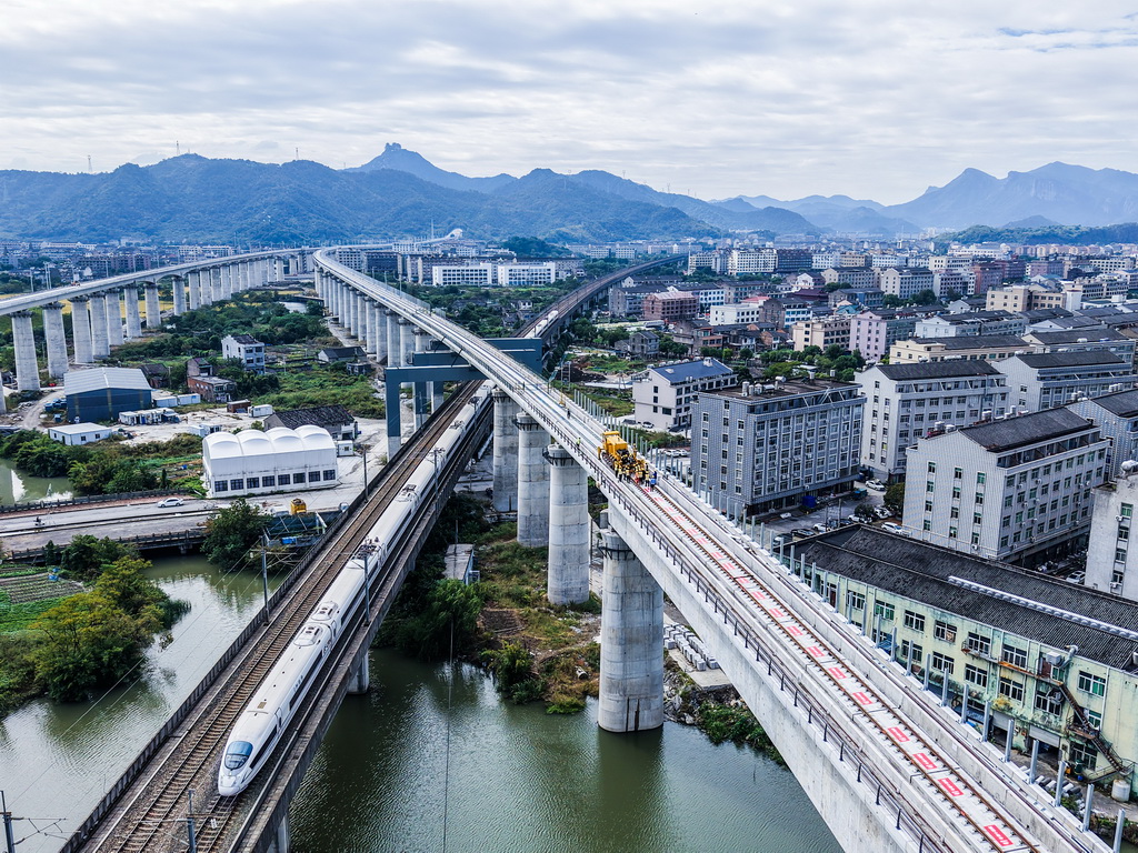 11月5日,在浙江省台州市杭台高铁温岭至玉环段施工作业现场,中铁十四局工作人员操作长轨牵引车进行铺轨作业(无人机照片)。
